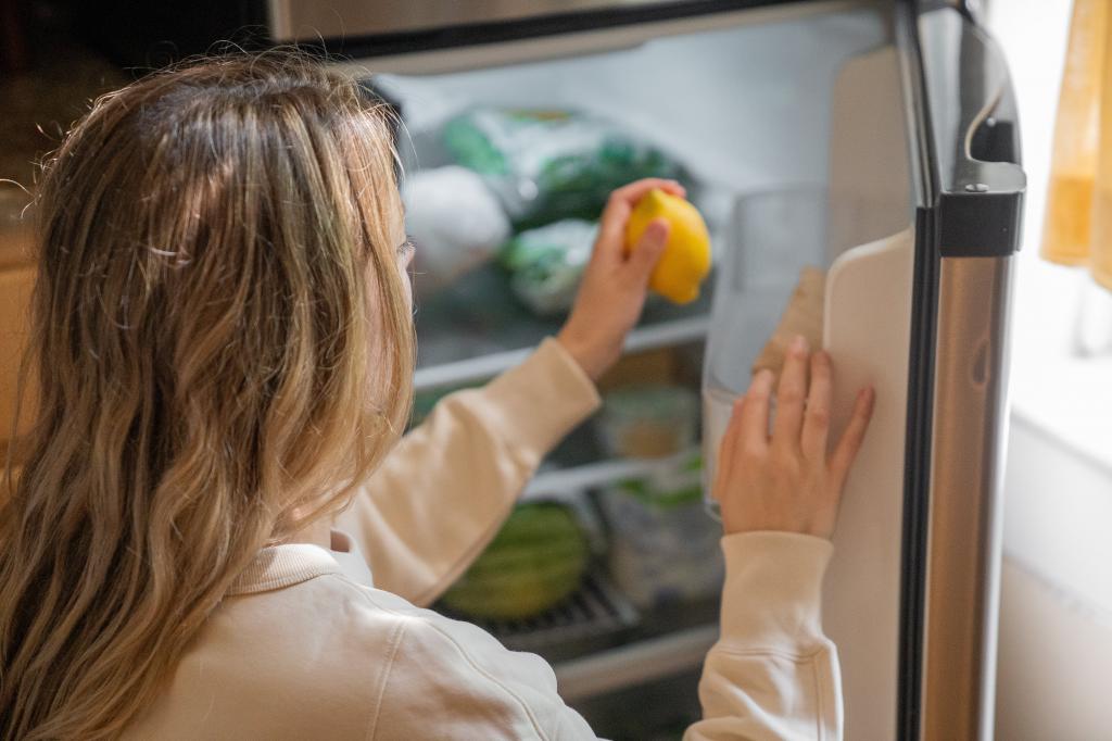 Frau beim Kühlschrank einräumen